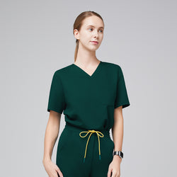 Image of Woman wearing a Zenir scrub top in pine green with a classic V-neck design, short sleeves, and a single chest pocket, paired with matching drawstring scrub pants, offering a professional and comfortable fit,Pine Green