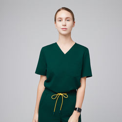 Image of Woman wearing a pine green scrub top with a front pocket, paired with matching pants and a yellow drawstring,Pine Green