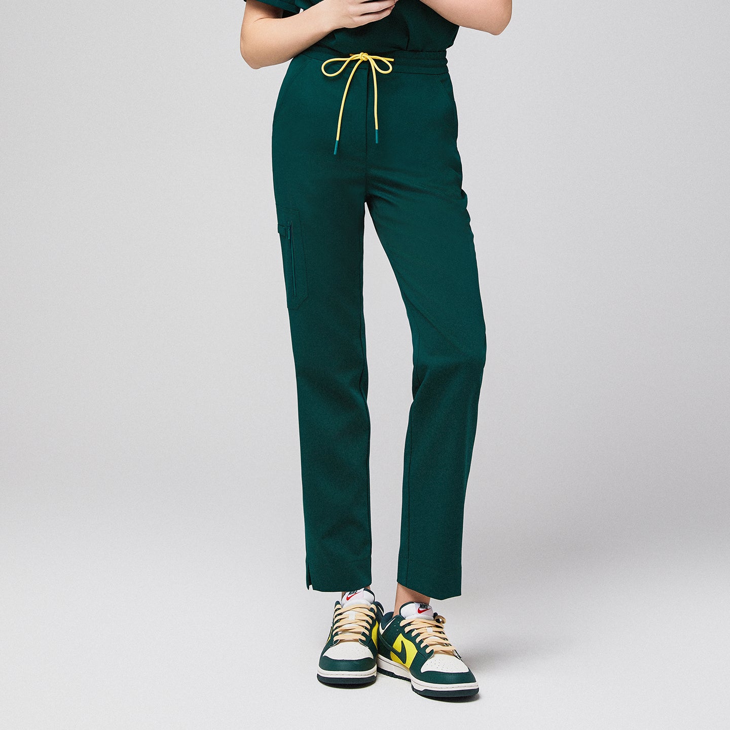 Green scrub pants with zipper pocket and drawstring waist, paired with green and yellow sneakers,Pine Green