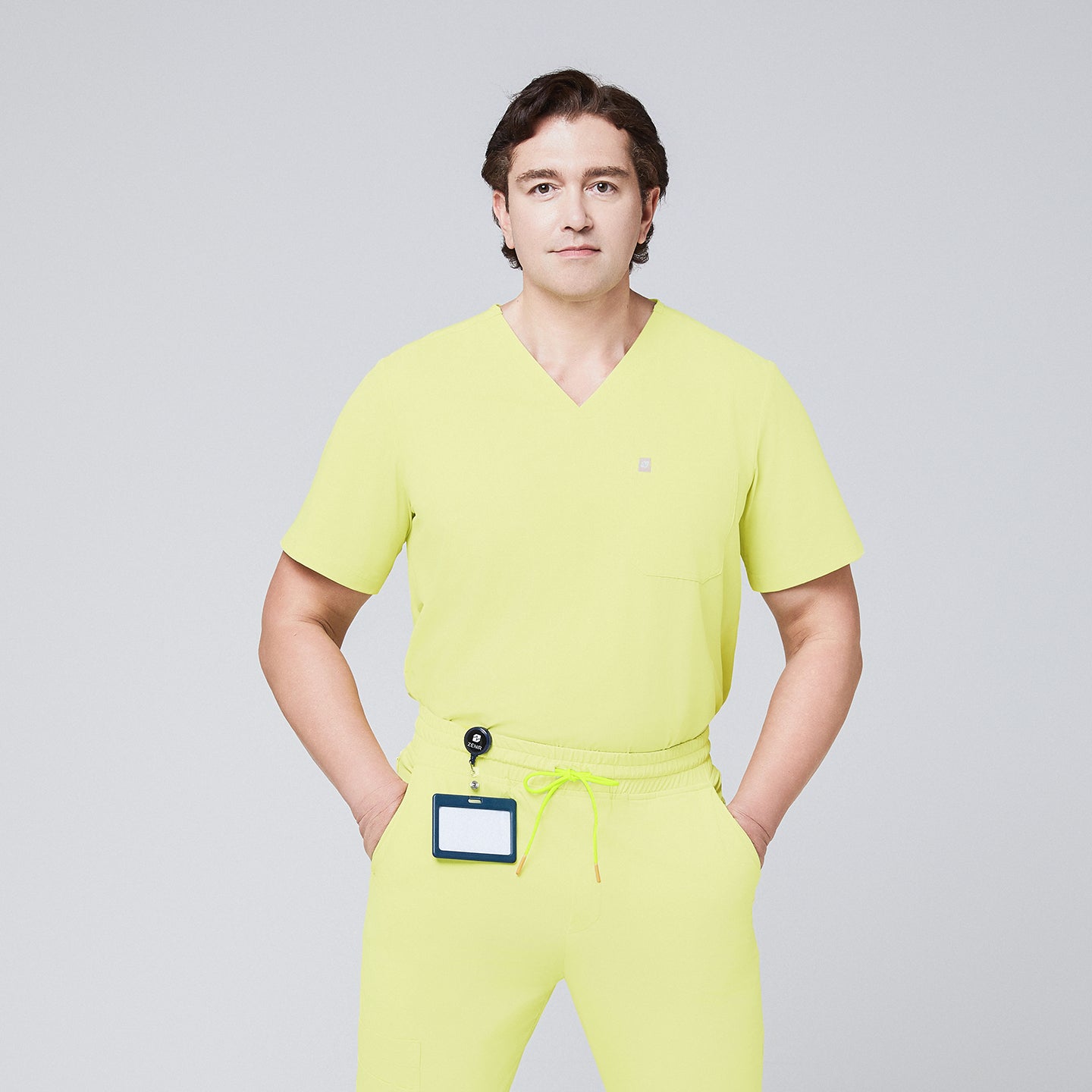 Male model wearing a pineapple yellow V-neck single-pocket scrub top with matching drawstring pants and a badge holder,Pineapple Yellow