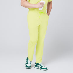 Image of Pineapple yellow straight-leg scrub pants with an adjustable drawstring waistband, paired with matching top and green sneakers,Pineapple Yellow