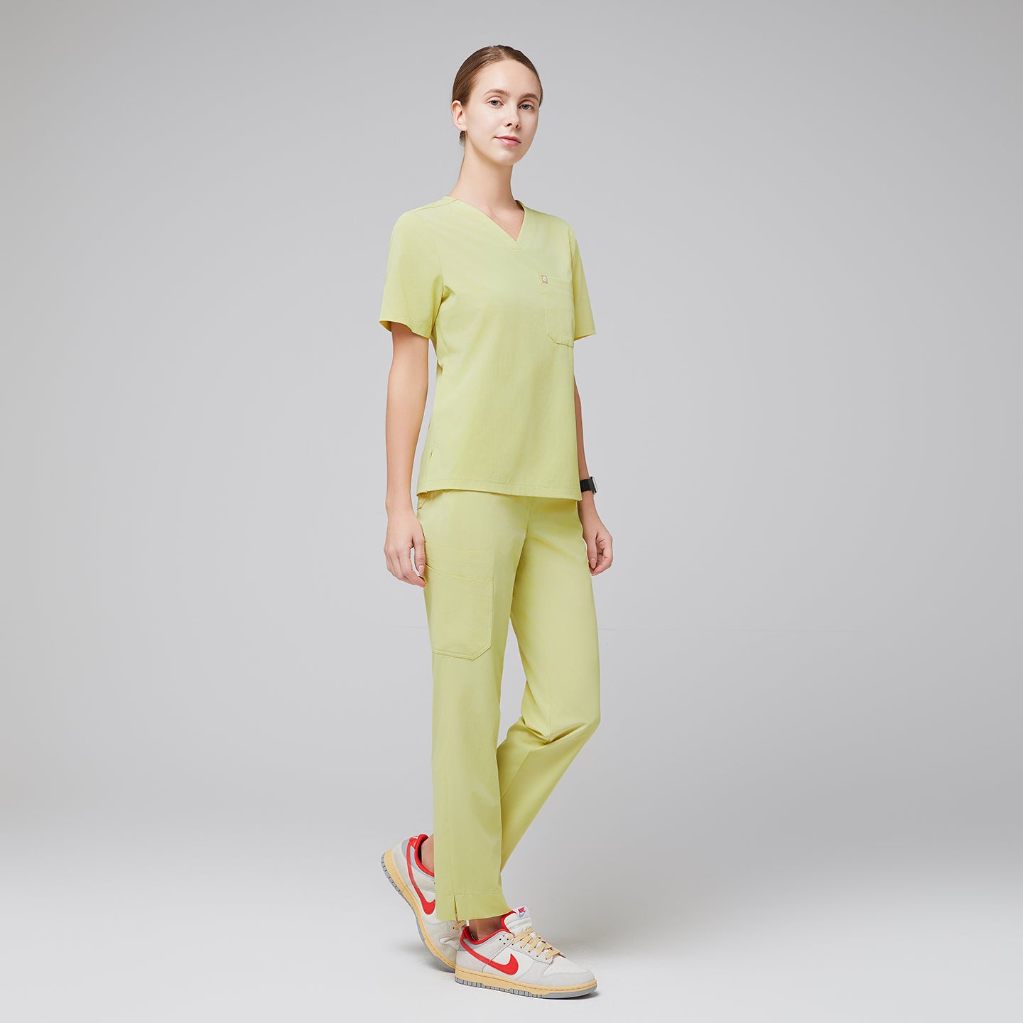 Female healthcare professional in a pineapple yellow scrub set, standing in a relaxed pose with orange-accented sneakers,Pineapple Yellow