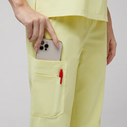 Image of Female placing phone into the side pocket of pineapple yellow scrub pants with pen holder,Pineapple Yellow