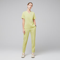 Image of Female wearing pineapple yellow V-neck scrub top and matching pants with beige sneakers,Pineapple Yellow