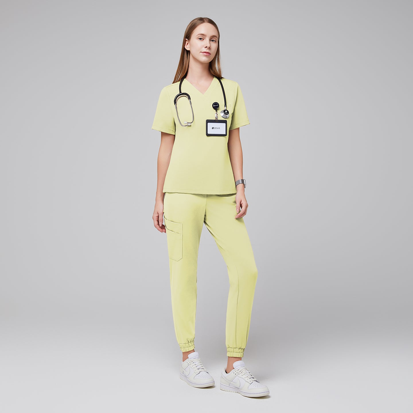 Woman wearing light yellow jogger scrubs with a stethoscope and ID badge, standing confidently in white sneakers,Pineapple Yellow