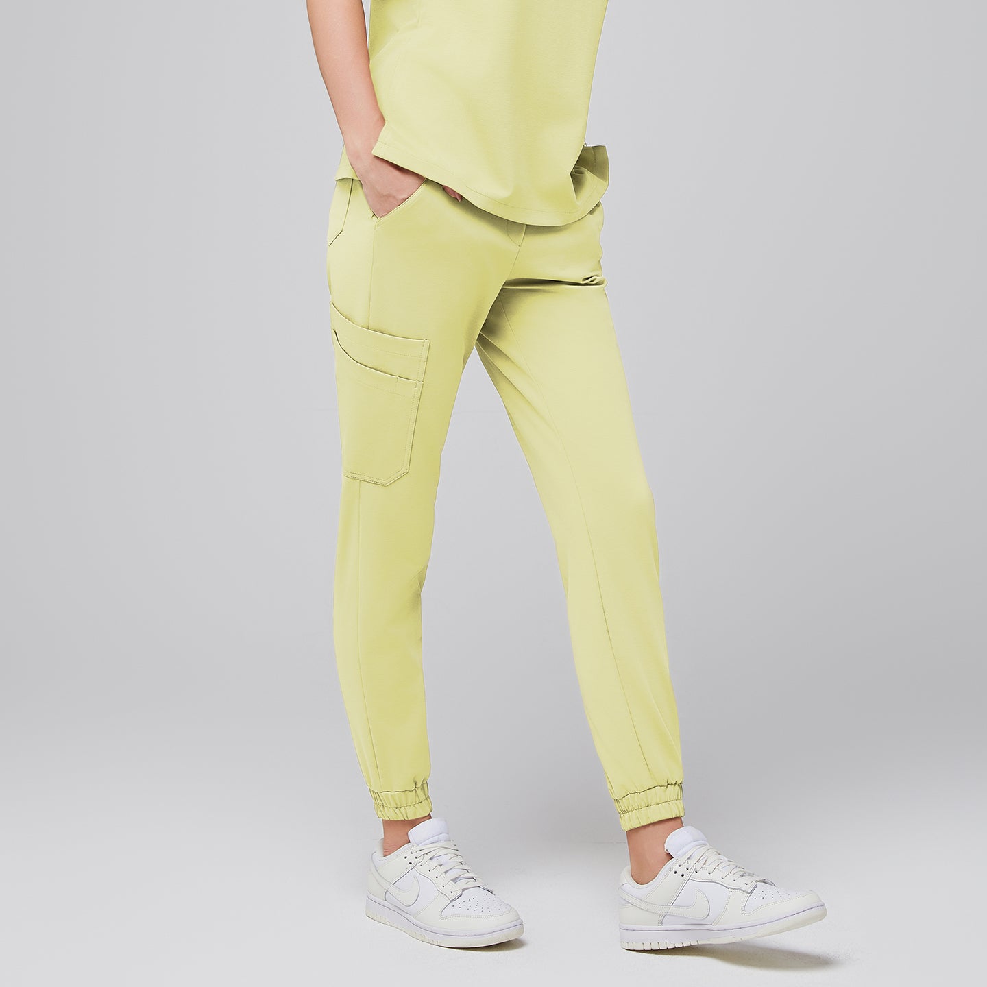 Close-up of light yellow jogger scrub pants with side pockets, worn with white Nike sneakers,Pineapple Yellow