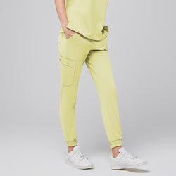 Image of Close-up of light yellow jogger scrub pants with side pockets, worn with white Nike sneakers,Pineapple Yellow