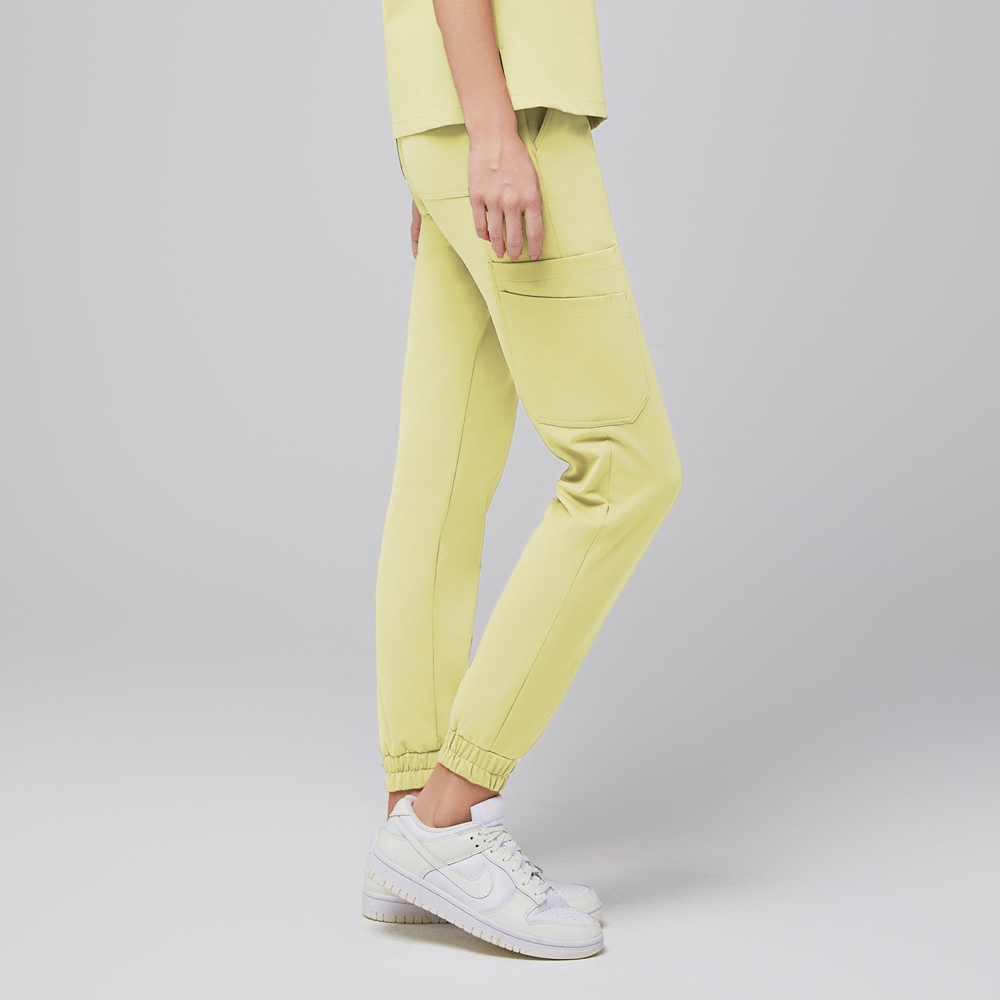 Side view of light yellow jogger scrub pants with side pockets, worn with white Nike sneakers,Pineapple Yellow