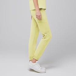 Image of Side view of light yellow jogger scrub pants with side pockets, worn with white Nike sneakers,Pineapple Yellow