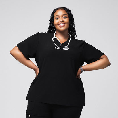 Female medical professional in a black scrub top with a stethoscope around her neck, standing with hands on her hips and smiling,Rich Black