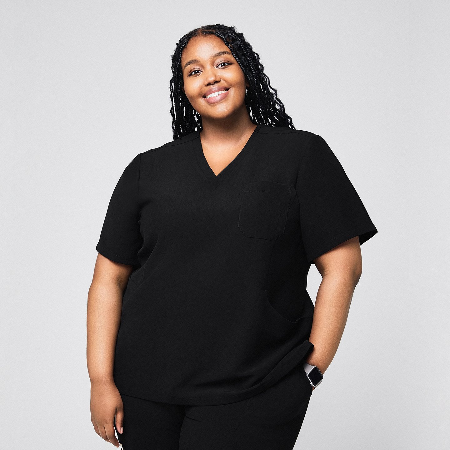 Smiling plus size model wearing the black scrub top, featuring a V-neck, short sleeves, and a relaxed fit against a neutral background,Rich Black