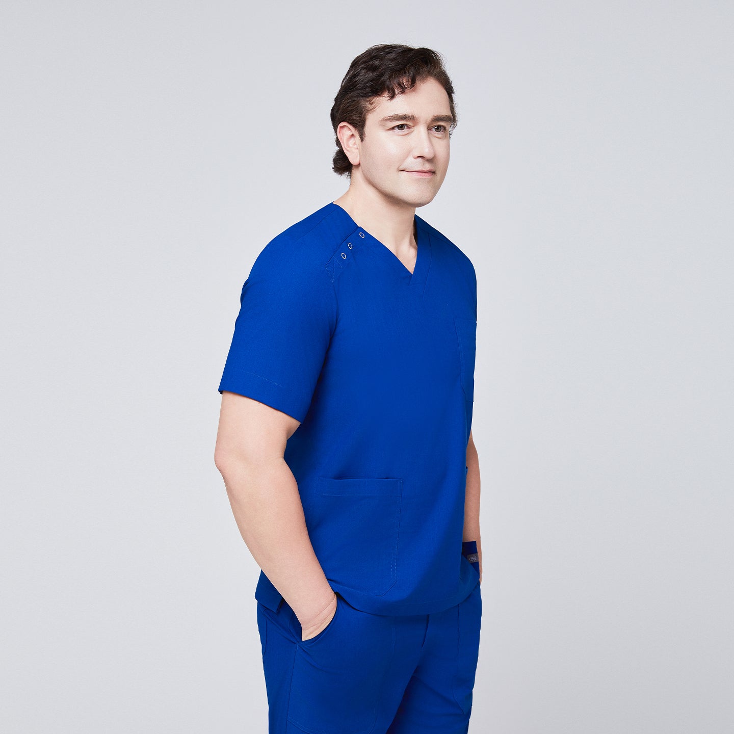 Man wearing Zenir royal blue 3-button scrub top with side profile, featuring chest and lower pockets,Royal Blue