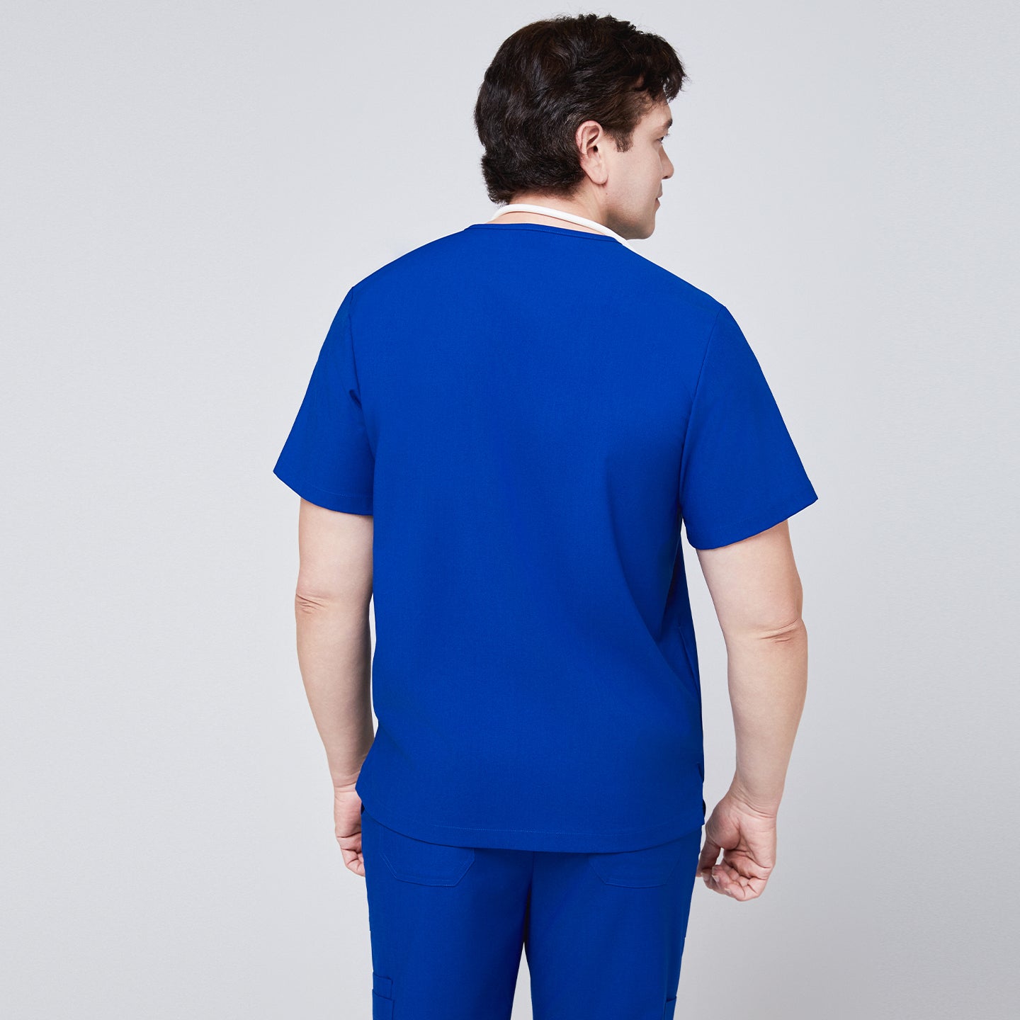 Close-up of a royal blue scrub top pocket with a person placing a smartphone inside,Royal Blue