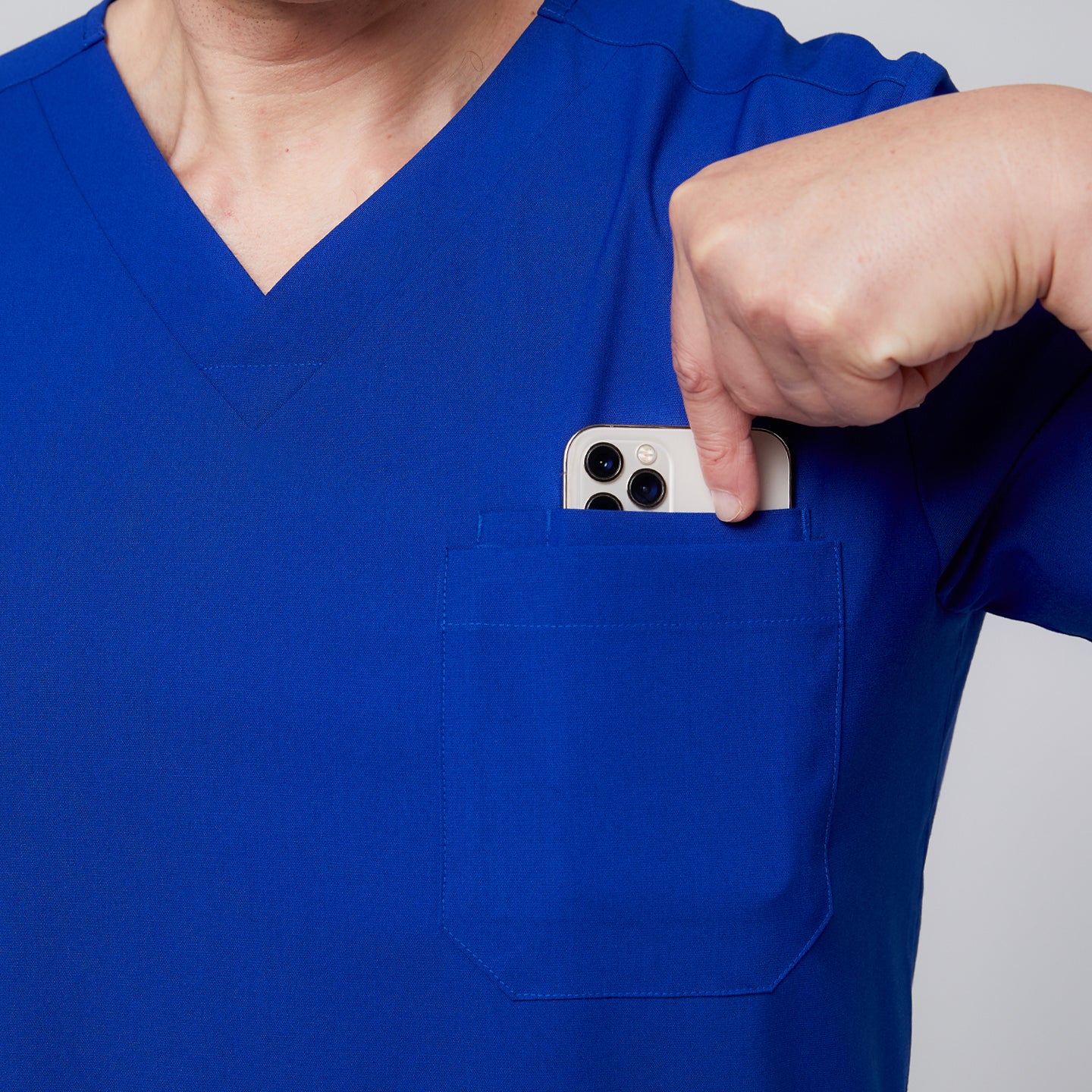 Close-up of a royal blue scrub top pocket with a person placing a smartphone inside,Royal Blue