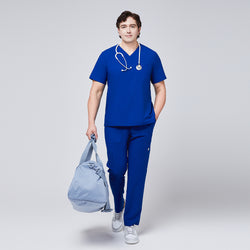 Image of Man wearing a royal blue V-neck scrub top with matching pants, carrying a light blue duffel bag and wearing a stethoscope around his neck,Royal Blue