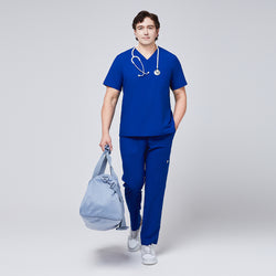 Image of Man wearing royal blue V-neck scrub top and 8-pocket straight scrub pants, accessorized with a stethoscope and light blue duffle bag,Royal Blue