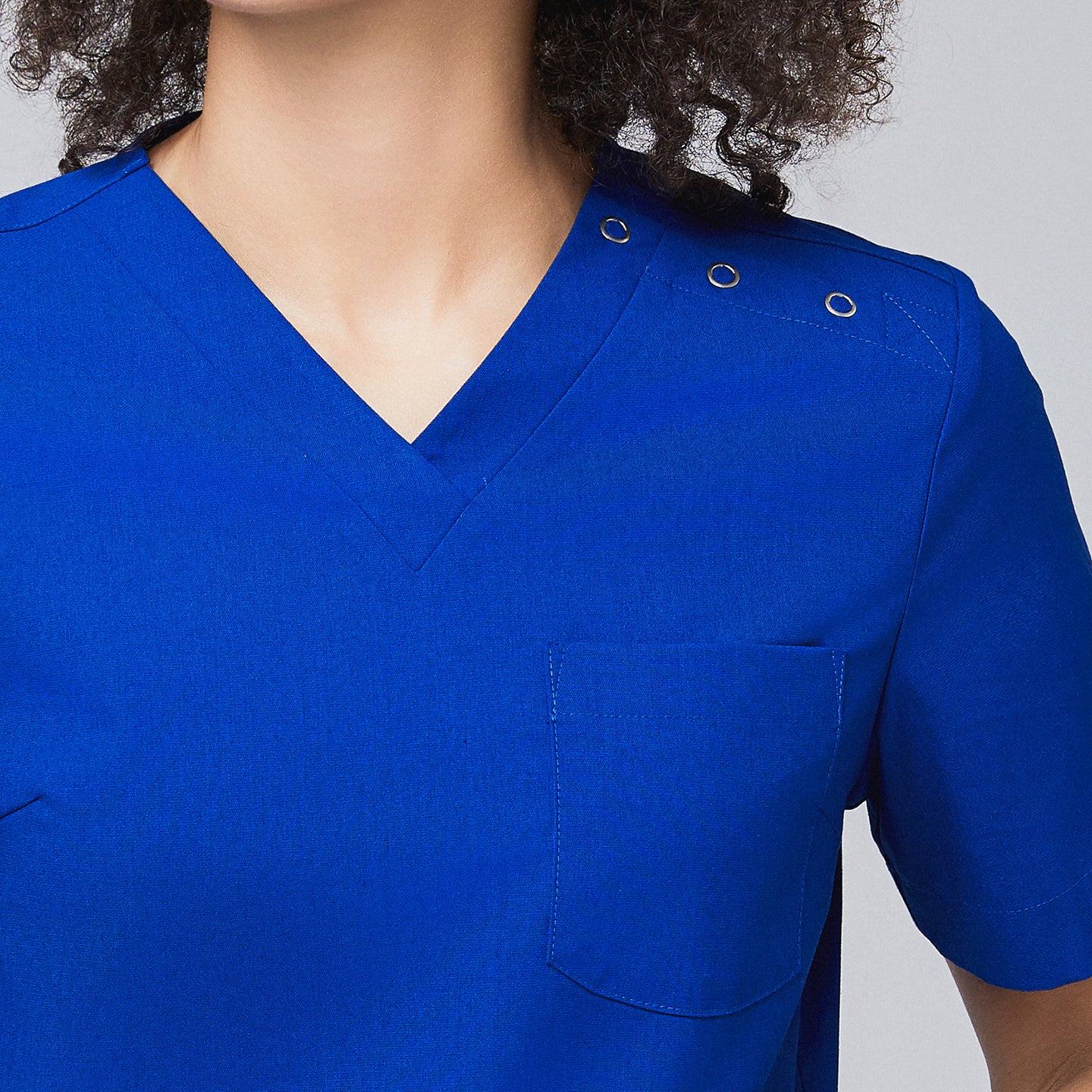 Close-up of a royal blue scrub top showing a V-neck design, shoulder button details, and a chest pocket,Royal Blue