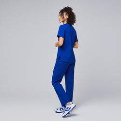 Image of A woman modeling a royal blue scrub set with a relaxed pose, showcasing the back design of the V-neck top with shoulder button details and straight-leg pants,Royal Blue