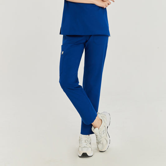 Front view of a woman wearing royal blue zipper slit scrub pants with a side pocket and white sneakers,Royal Blue