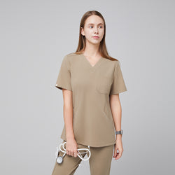 Image of Female model wearing a sand beige soft stretch scrub top with short sleeves and a V-neckline, holding a stethoscope in her hand,Sand Beige