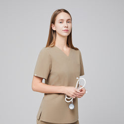 Image of Female model wearing a sand beige soft stretch scrub top, holding a white stethoscope, shown in a half-side view,Sand Beige