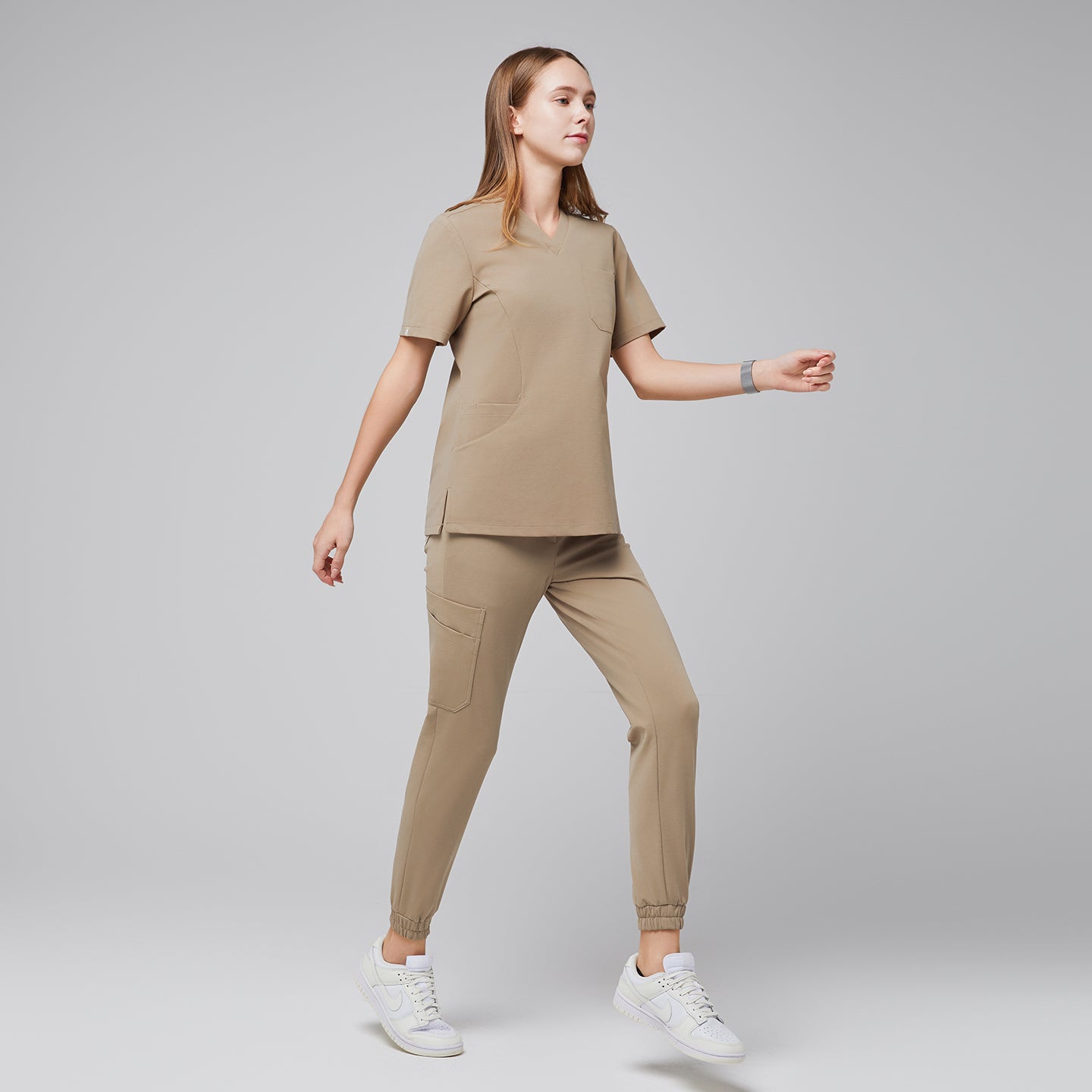 Comfortable scrub set with a V-neck top and jogger pants, shown in a side view during movement, highlighting its practical design,Sand Beige