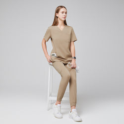 Image of Professional scrub set styled with a relaxed fit top and elastic ankle jogger pants, paired with white sneakers, modeled in a seated position on a stool for a polished and comfortable appearance,Sand Beige