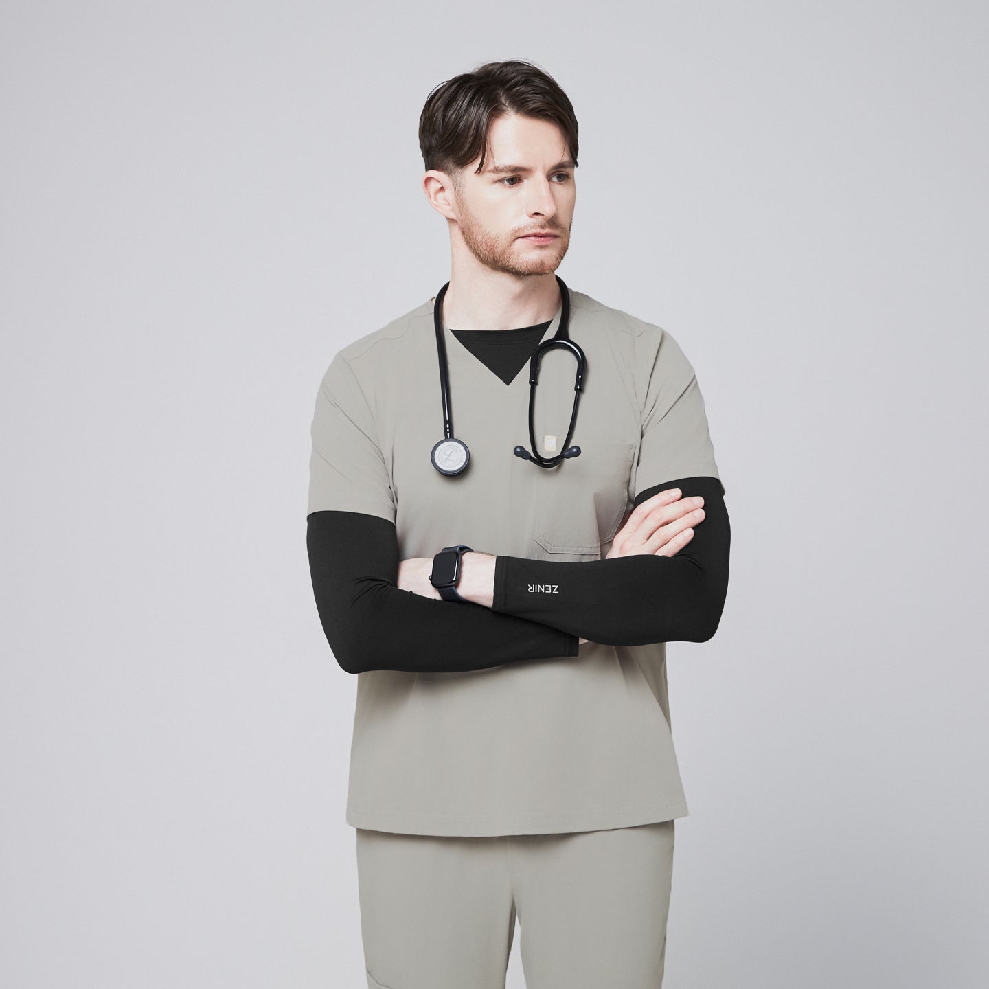 Male model wearing a sand khaki V-neck single-pocket scrub top with a stethoscope and crossed arms,Sand Khaki