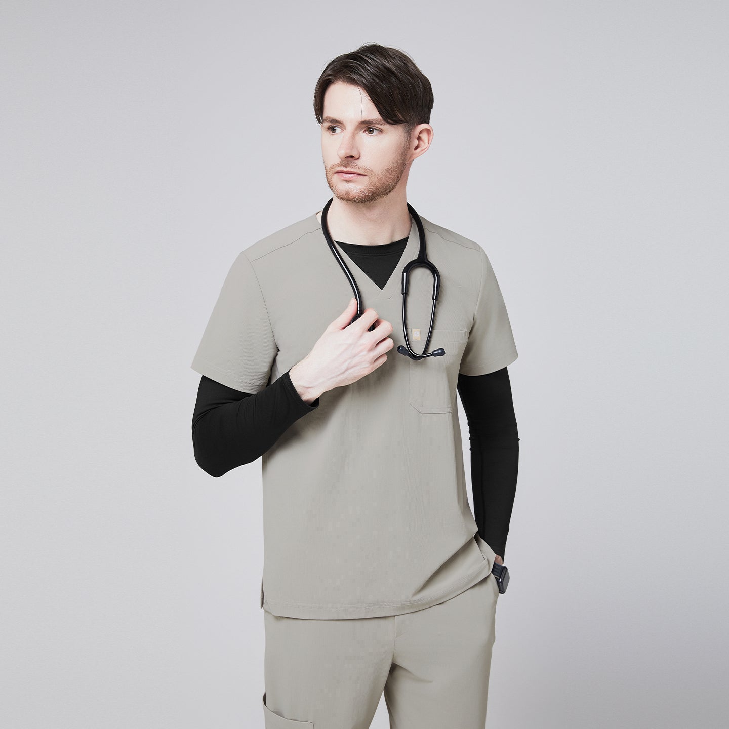 Male model wearing a sand khaki V-neck single-pocket scrub top with a stethoscope around his neck,Sand Khaki