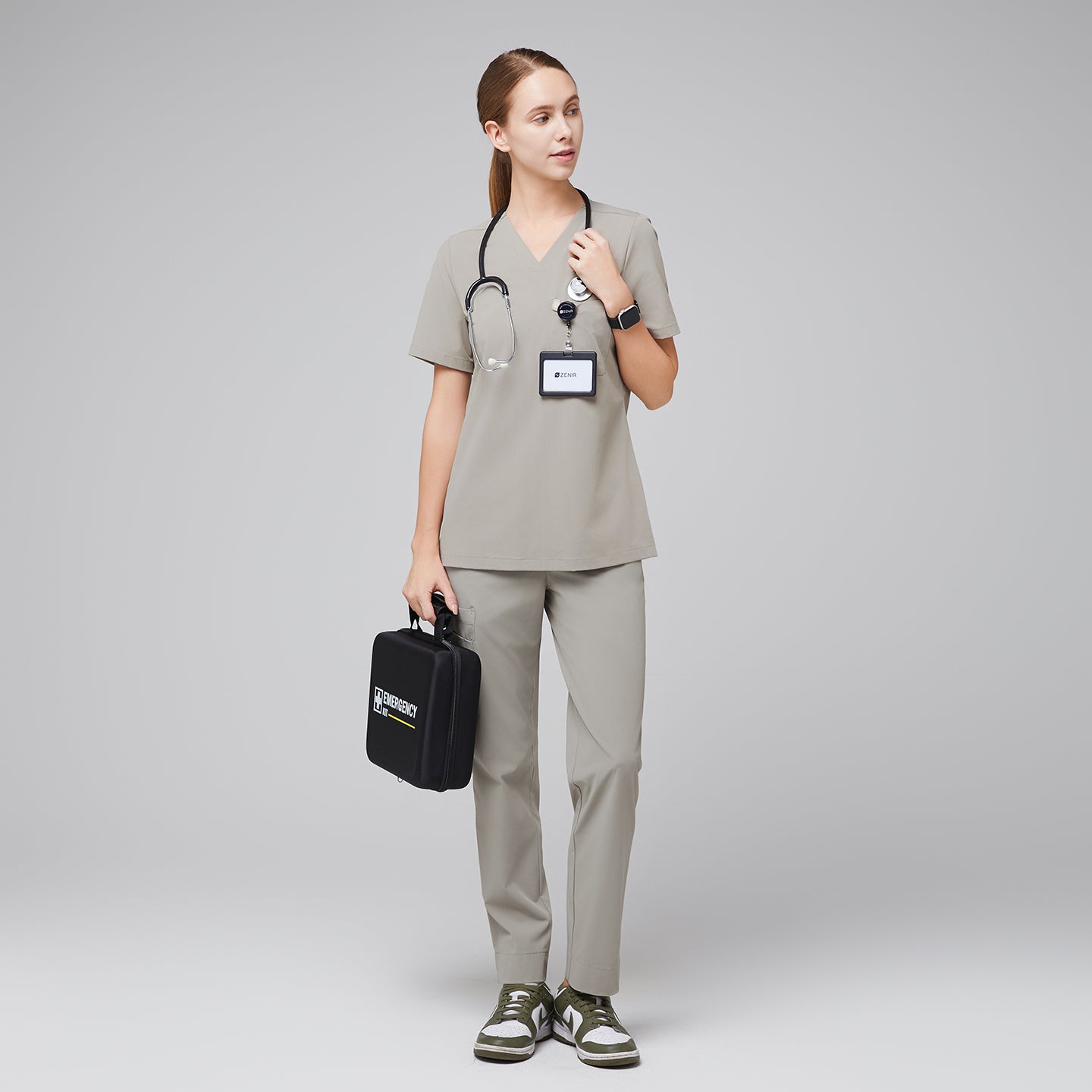 Full-body view of a female healthcare professional in a sand khaki scrub set, holding a black emergency kit and wearing a stethoscope and name badge,Sand Khaki