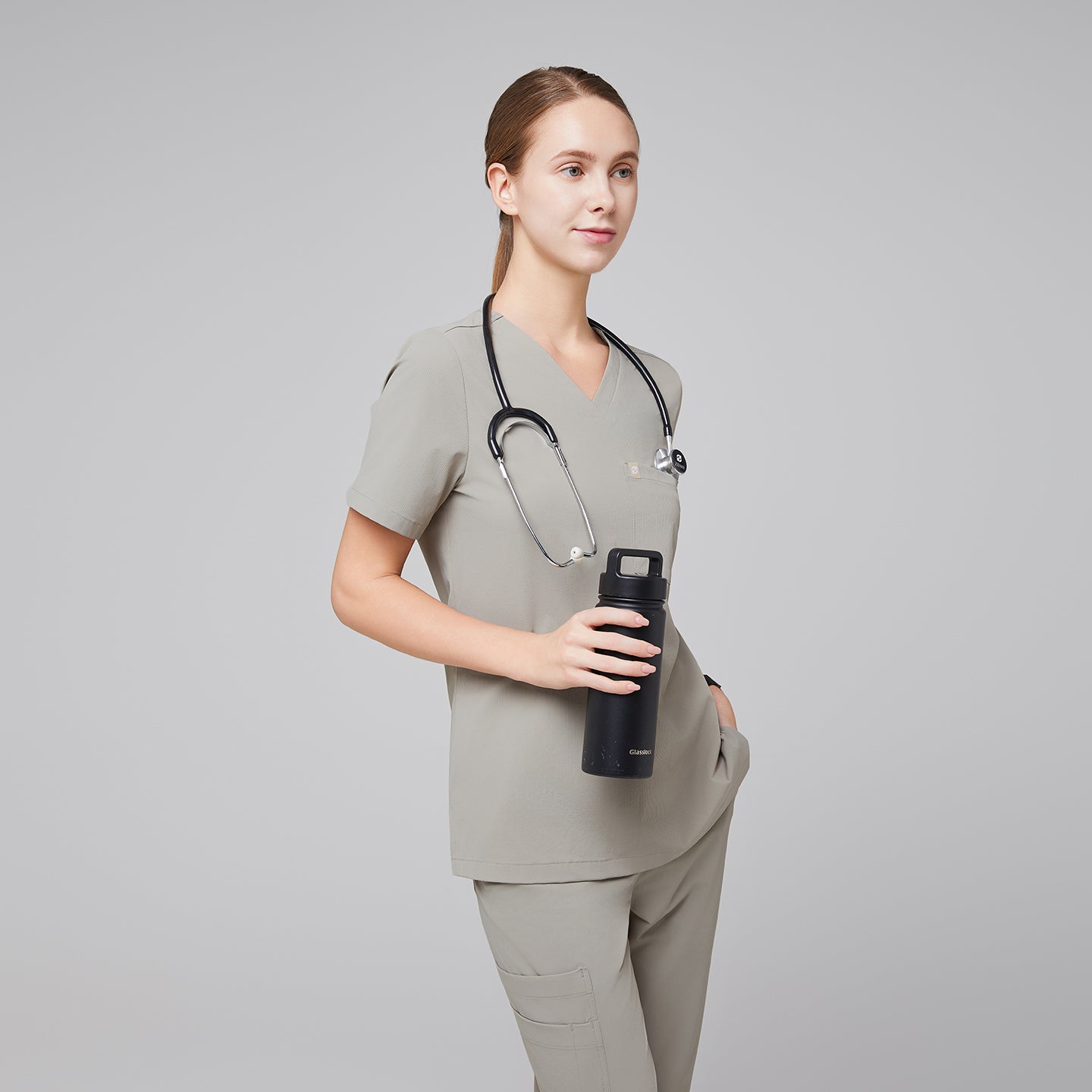 Female healthcare professional in a sand khaki scrub set with a stethoscope, holding a black water bottle,Sand Khaki