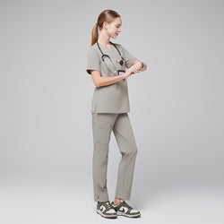 Image of Female healthcare professional in a sand khaki scrub set, wearing a stethoscope and checking the time on a smartwatch, full-body side view,Sand Khaki