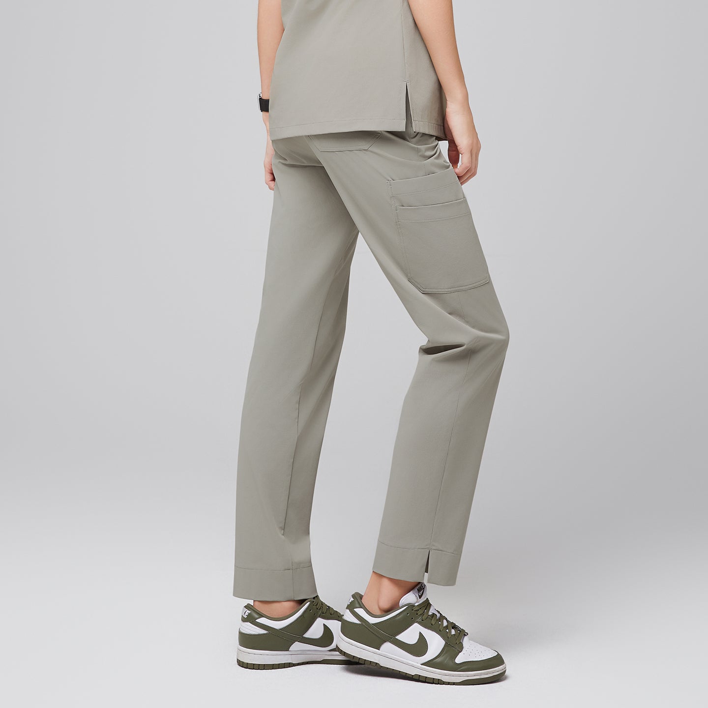 Female wearing khaki scrub pants, shown from the back, with a pocket detail and green and white sneakers,Sand Khaki