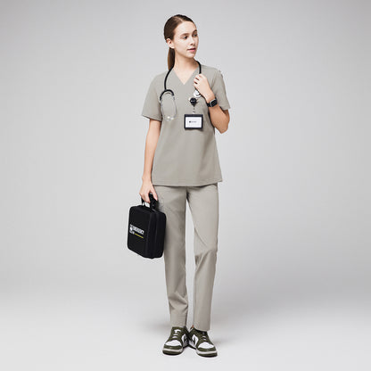 Female healthcare professional in khaki scrubs holding an emergency kit with stethoscope and ID badge,Sand Khaki