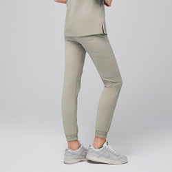 Image of Back view of sand khaki jogger scrub pants showcasing a tailored fit with back pockets and elasticized cuffs, paired with sleek silver sneakers for a modern and professional appearance, Sand Khaki