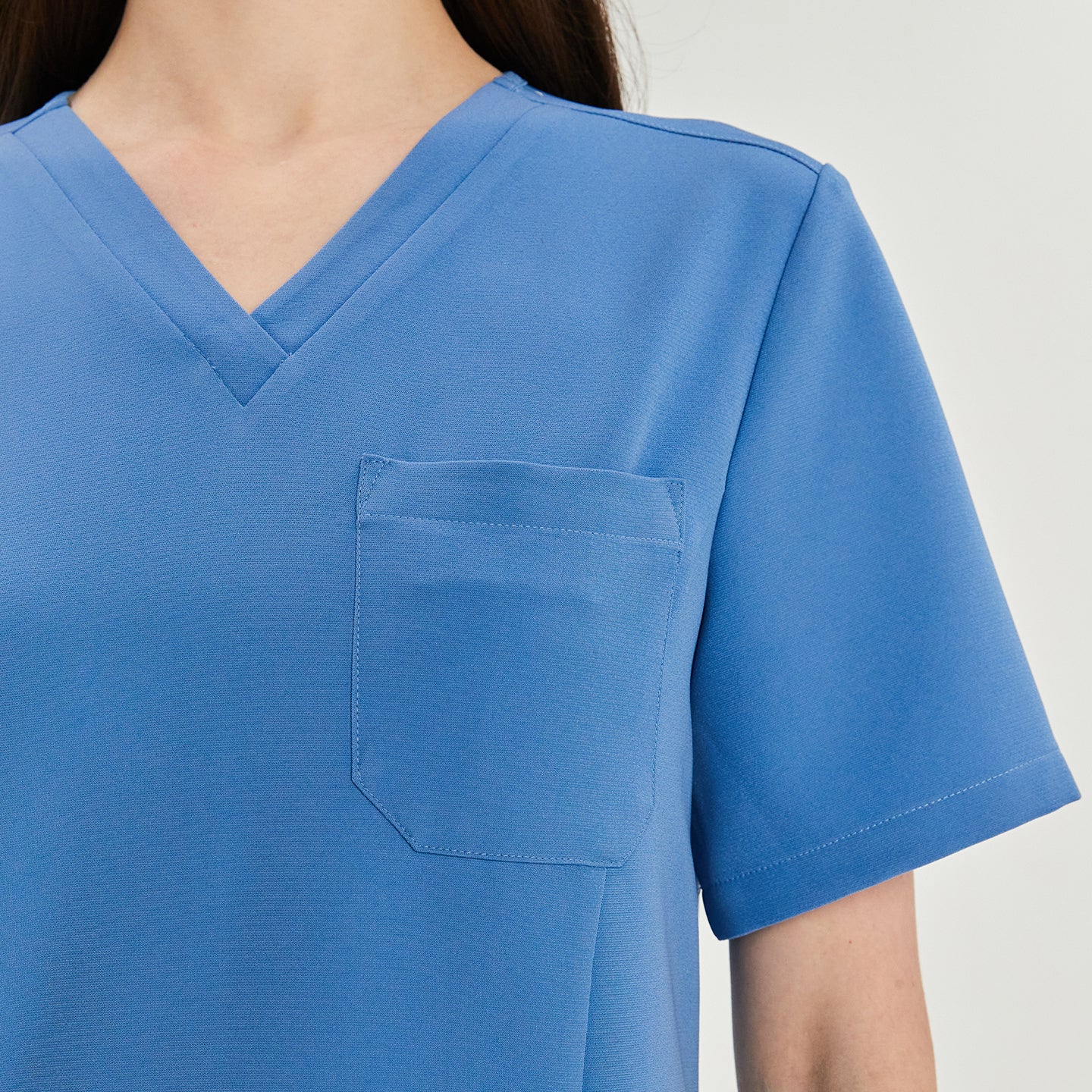 Close-up of a woman's scrub top, showing the V-neck and chest pocket details,Sky Blue