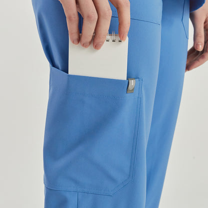 Close-up of a woman’s hand placing a notepad into the pocket of sky blue zipper slit scrub pants,Sky Blue