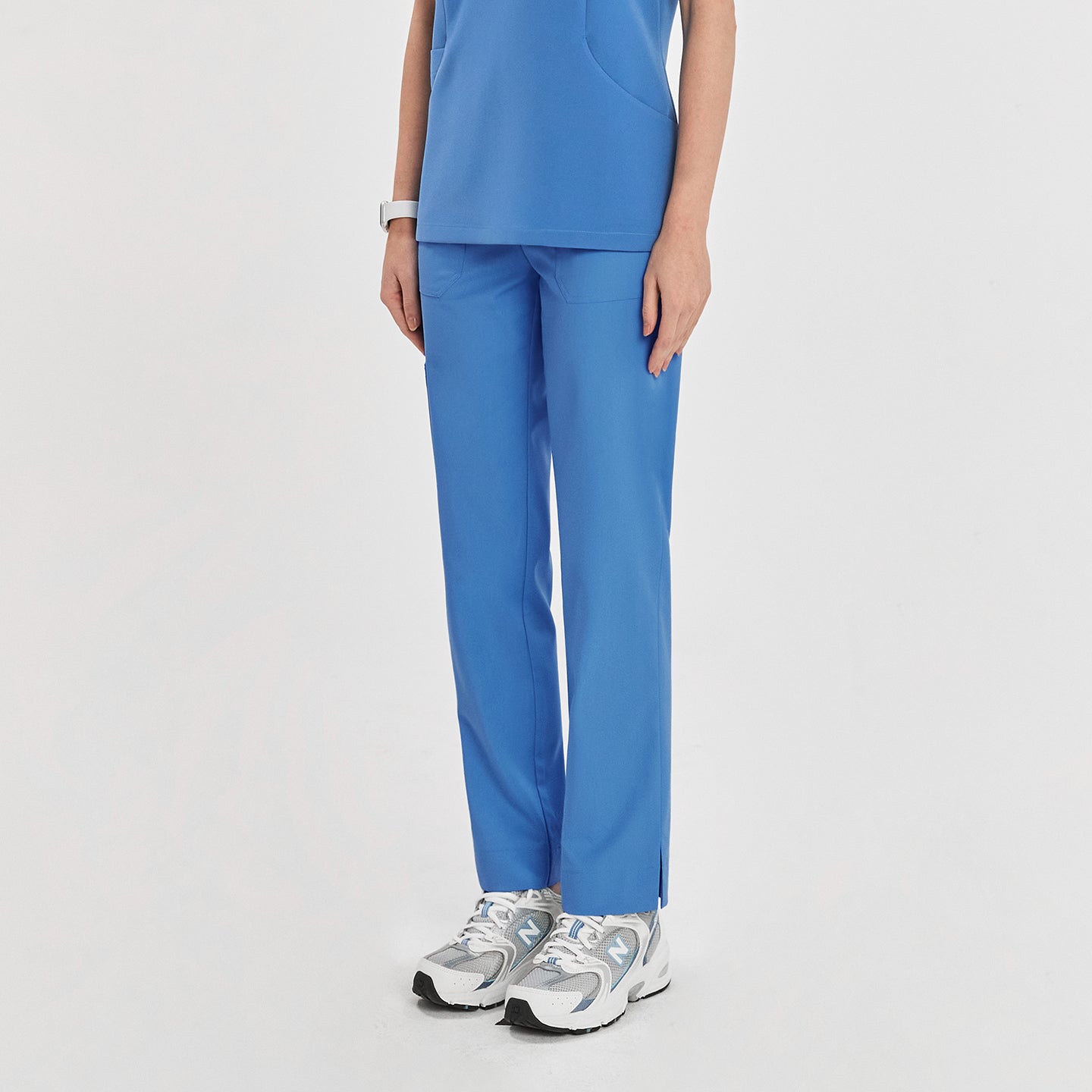 Woman in sky blue zipper slit scrub pants with a side pocket, shown from the front with a matching scrub top,Sky Blue
