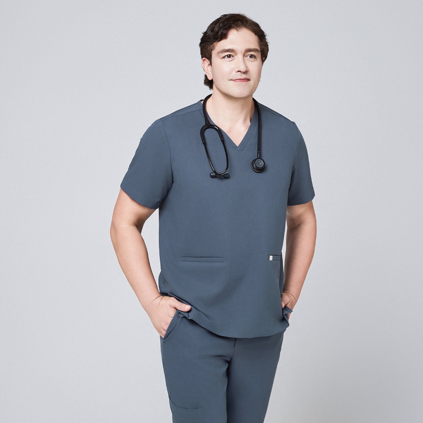 Man wearing a smoky blue scrub set with a double-pocket V-neck top, accessorized with a black stethoscope,Smoky Blue