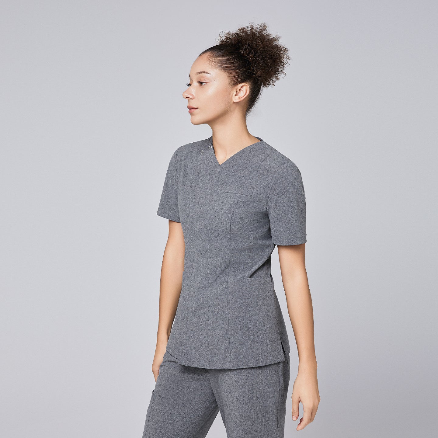 Woman wearing Zenir soft gray front zipper scrub top with side profile, paired with matching pants,Ash Gray