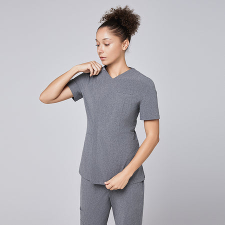 Woman wearing Zenir soft gray front zipper scrub top, adjusting the zipper, paired with matching pants,Ash Gray