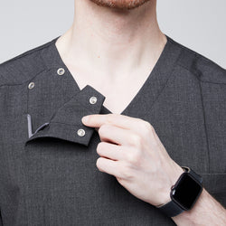 Image of Close-up of a man demonstrating the functional snap buttons on the shoulder of a soft gray scrub top, highlighting its unique design detail,Charcoal Gray