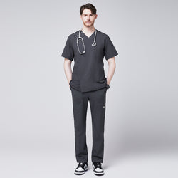 Image of Man in a soft gray scrub top with a V-neck and shoulder button detail, styled with matching pants, wearing a stethoscope around his neck and posing with hands in pockets,Charcoal Gray