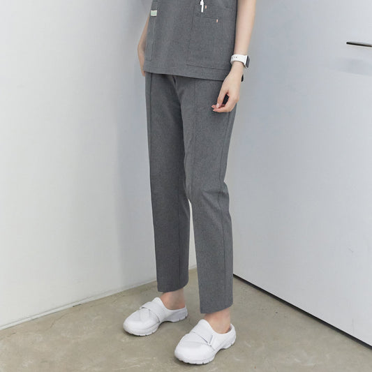 A woman standing, wearing Soft Gray W Line Banding Scrub Pants with a matching top, showing the full length of the pants,Soft Gray