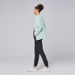 Image of A side profile of a woman wearing a soft mint comfort cardigan paired with black jogger-style scrub pants and white sneakers, showcasing the cardigan's relaxed yet professional silhouette,Soft Mint