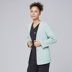 Image of A professional woman wearing a soft mint comfort cardigan over a black scrub top, gently adjusting the cardigan's fit with a poised expression, highlighting its modern and polished design.Soft Mint