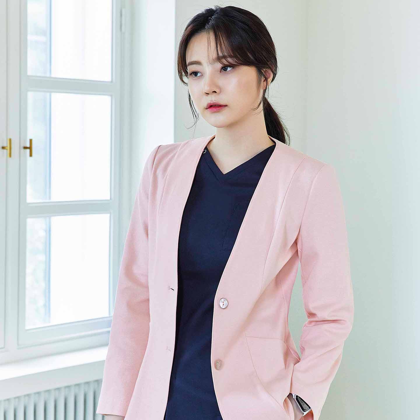 Woman in soft pink Zenir jacket over navy top, standing with hand in pocket, looking slightly away,Soft Pink
