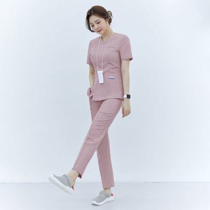 A woman wearing Soft Pink Line Banding Scrub Pants paired with a matching top and gray shoes, showcasing the full-body front view and fit of the outfit,Soft Pink