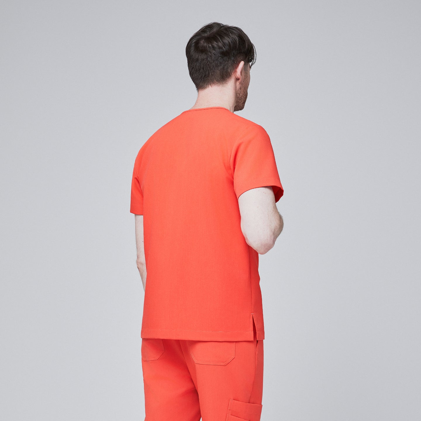 Man wearing tiger orange scrubs with short sleeves and matching pants, facing away,Tiger Orange