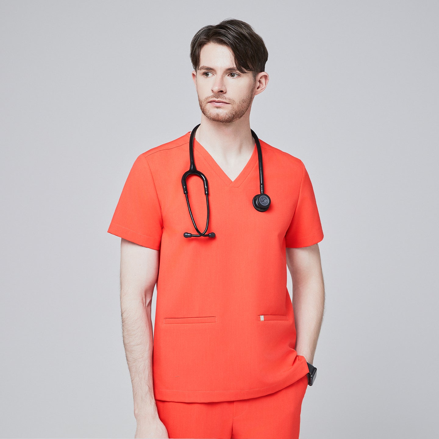 Man wearing tiger orange scrubs with a V-neck and double pockets, accessorized with a black stethoscope,Tiger Orange